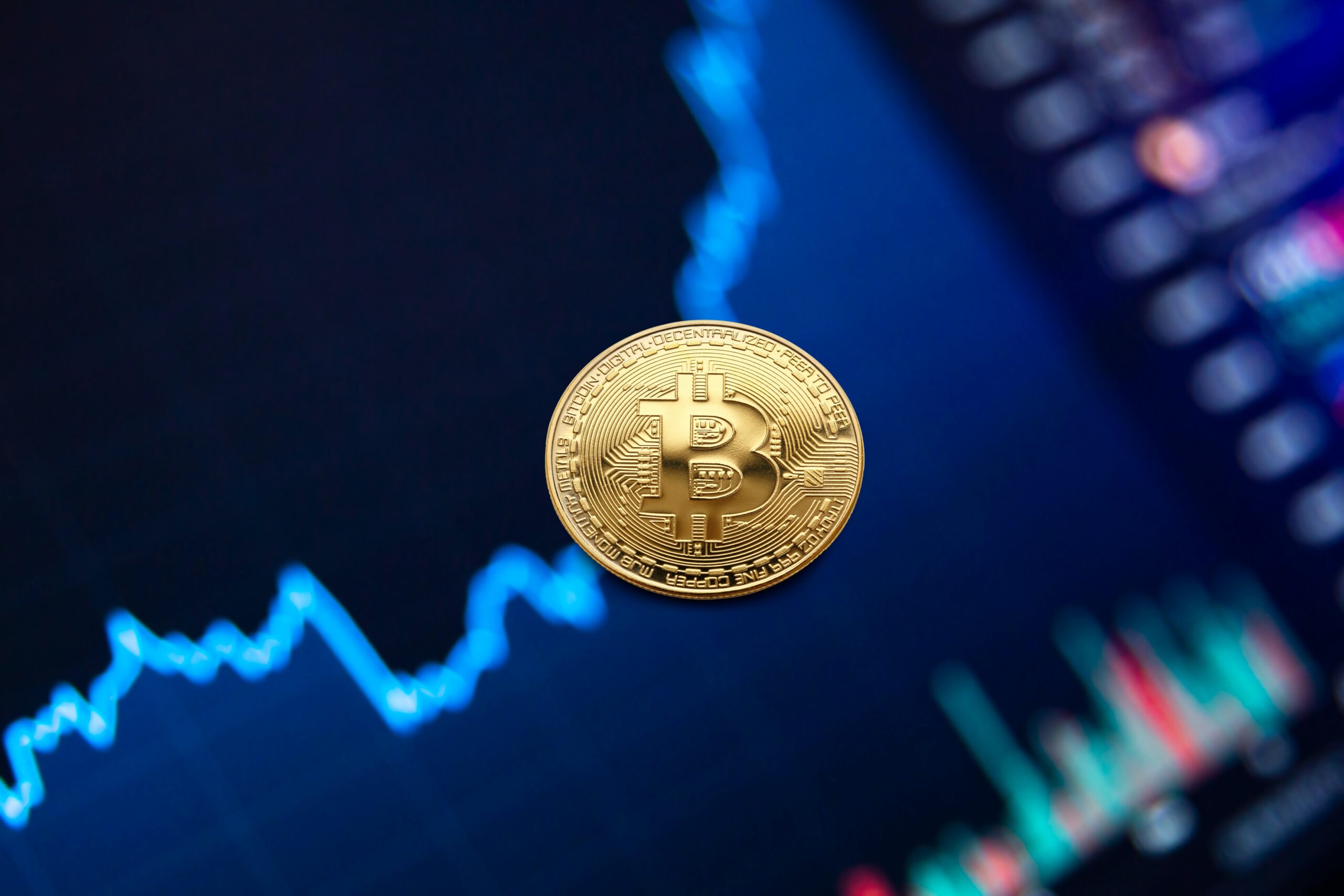 Moneta Bitcoin na tle wykresu giełdowego
