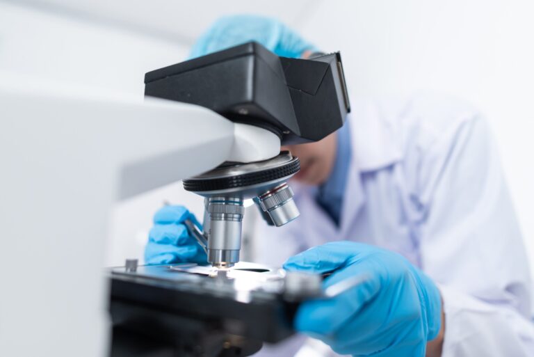 Naukowiec bada próbki pod mikroskopem laboratoryjnym