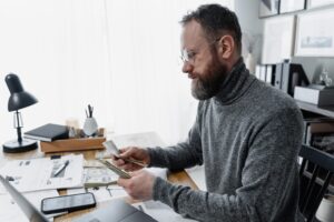 Mężczyzna liczy pieniądze przy biurku z dokumentami.