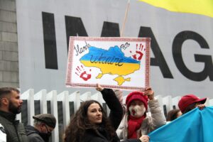 Protest: plakat 'Hands off Ukraine' i flaga.