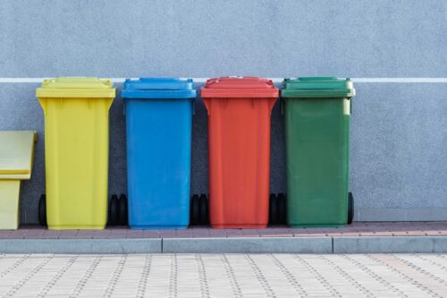 Kolorowe kosze na śmieci przed ścianą