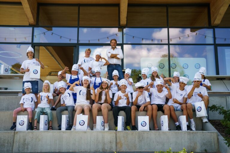 Grupa dzieci w białych koszulkach i czapkach kucharskich