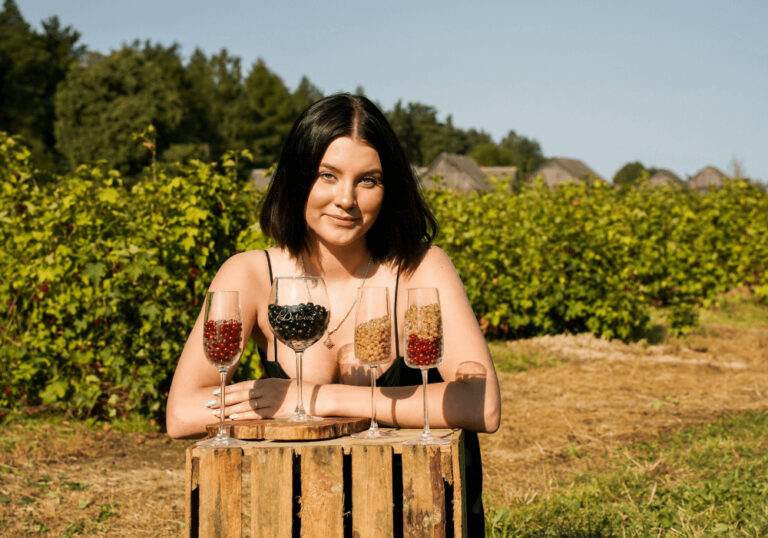 Kobieta w winnicy z kieliszkami pełnymi jagód.