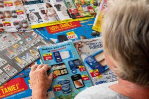 Starsza osoba przegląda gazetki promocyjne z ofertami.