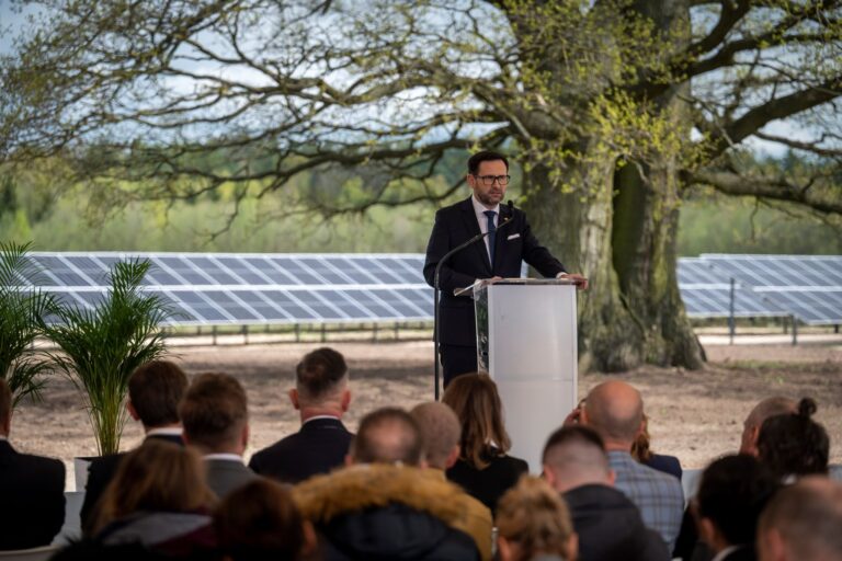 Mężczyzna przemawia na zewnątrz obok paneli słonecznych.