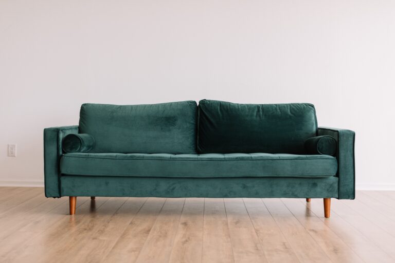 Zielona sofa na drewnianej podłodze.