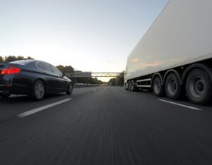 Samochód i ciężarówka na autostradzie o zmierzchu.