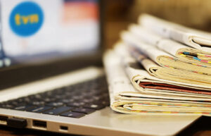 Laptop i stos gazet na stole