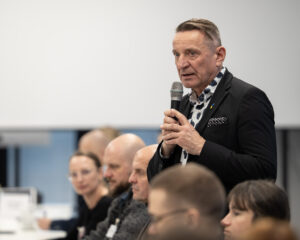 Mężczyzna przemawia na spotkaniu biznesowym z mikrofonem.