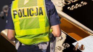 Policjant przy złotym sztabie z dokumentami
