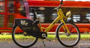 Żółty rower miejski przed czerwonym tramwajem