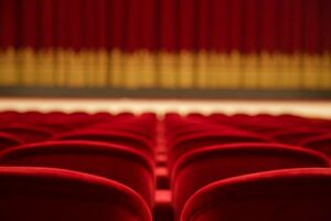 Czerwone fotele na sali teatralnej z zasłoną