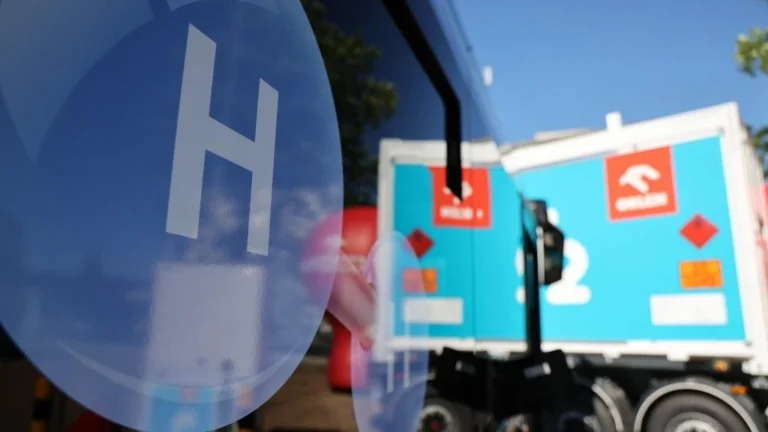 Cysterna wodorowa na tle ciężarówki transportowej.