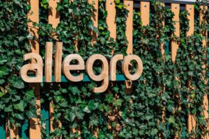 Logo Allegro na tle zielonych liści