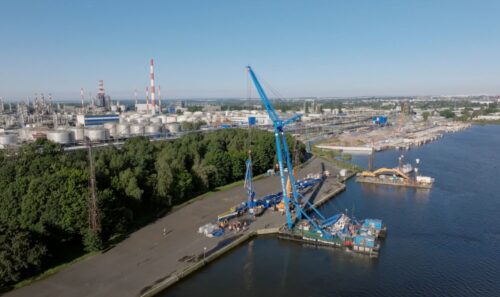Widok na port i przemysłowe instalacje nad wodą.
