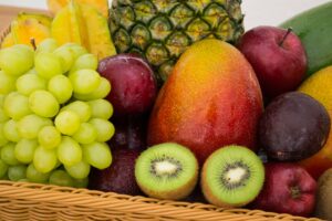 Owoce w koszu: winogrona, kiwi, mango, ananas.