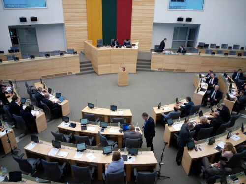 Obrady parlamentu z flagą Litwy na ścianie.
