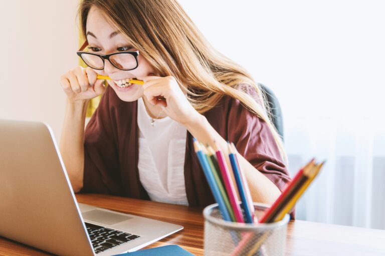 Stresująca praca przy laptopie, kobieta gryzie ołówek.