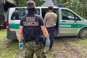Straż graniczna przy pojeździe na leśnej drodze.