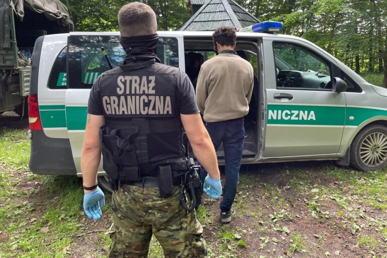 Straż graniczna przy pojeździe na leśnej drodze.