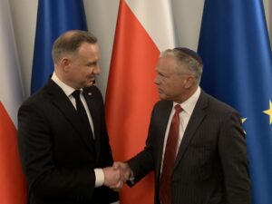 Dwóch mężczyzn podaje sobie ręce, flagi w tle.