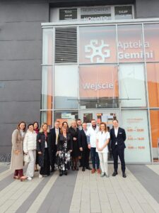 Grupa osób przed Apteką Gemini w Polsce.