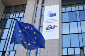 Flaga UE przed budynkiem z logo i napisem.