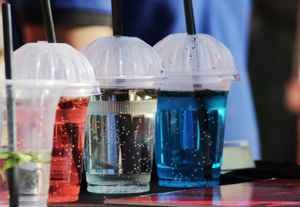 Kolorowe napoje gazowane w plastikowych kubkach.