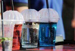 Kolorowe napoje gazowane w plastikowych kubkach.