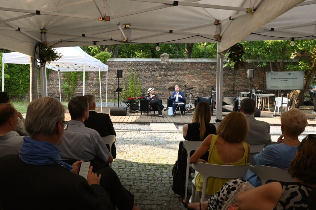 Debata na zewnątrz pod namiotem, dwóch mówców, publiczność.