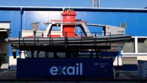 Łódź ratunkowa na kontenerze przed niebieskim budynkiem.