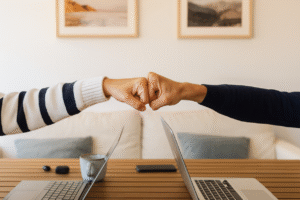 Dwie osoby zbijają pięści nad laptopami