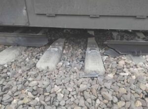 Uszkodzone podkłady kolejowe pod pociągiem.