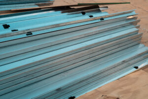 Stalowe belki konstrukcyjne, stosy na drewnianej podłodze.