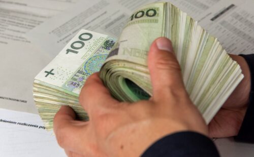 Ręce liczące polskie banknoty stuzłotowe.