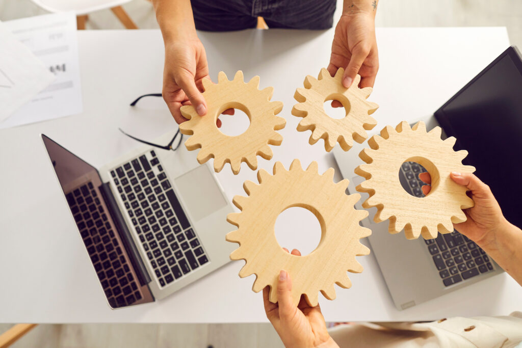 Ludzie trzymają drewniane tryby nad laptopami.