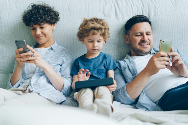 Rodzina używa urządzeń mobilnych na kanapie.
