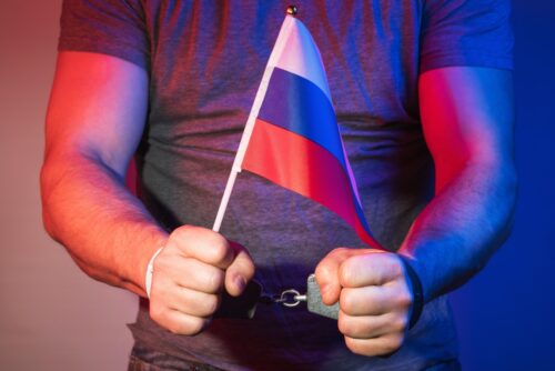Człowiek zrosyjsą flagą i kajdanki
