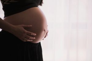 Kobieta w czarnej bieliźnie trzyma dłonie na brzuchu