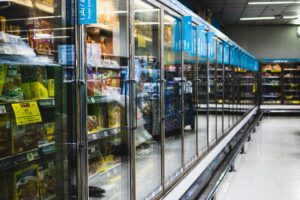 Oświetlone półki z produktami za szklanymi drzwiami chłodziarki