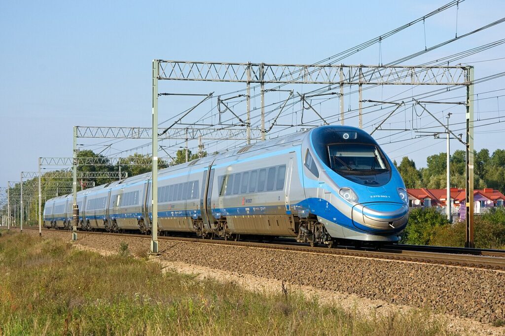 Niebiesko-srebrny pociąg Pendolino na zelektryfikowanej trasie