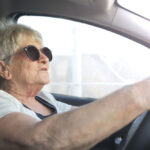 Kobieta w okularach prowadzi samochód.