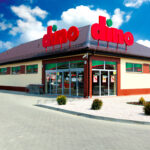 Fasada sklepu z dużym czerwonym logo na dachu.